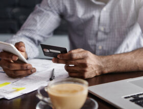 Man som håller kreditkort och telefon i handen